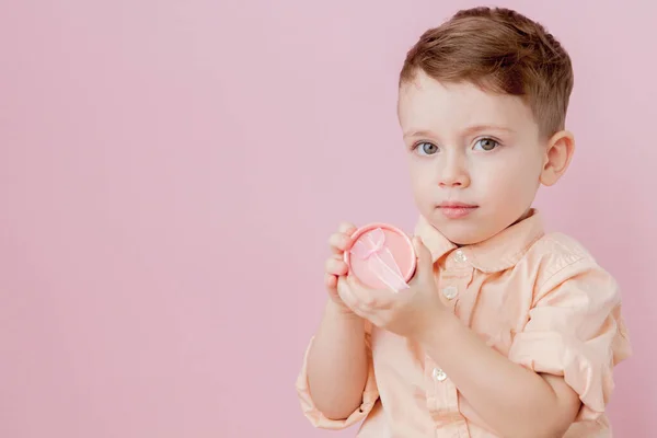 Gelukkig jongetje met een cadeau. Foto geïsoleerd op roze achtergrond. Lachende jongen houdt huidige vak. Concept van vakantie en verjaardag — Stockfoto