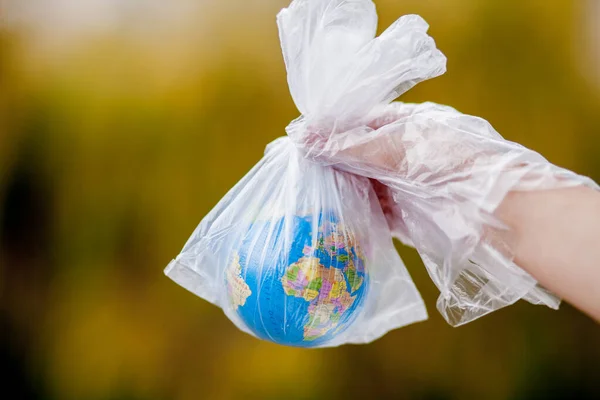 The human hand holds the planet earth in a plastic bag. The concept of pollution by plastic debris. Global warming due to greenhouse effect. — Stock Photo, Image