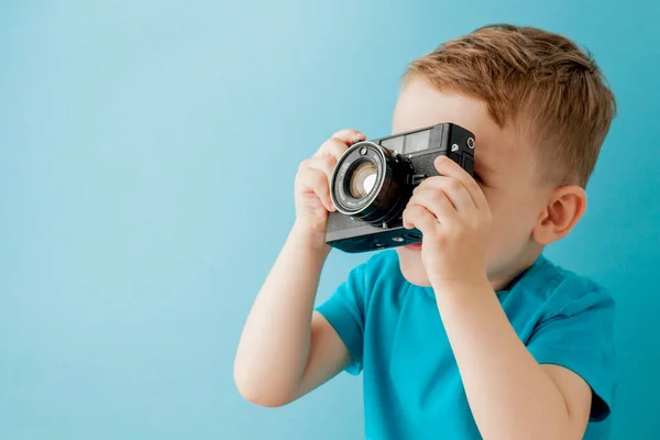 Kisfiú egy régi fényképezőgéppel a kék háttéren — Stock Fotó