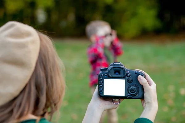 Kadın fotoğrafçı dışarıda geçirmek için çocuğun fotoğrafını çekiyor. — Stok fotoğraf