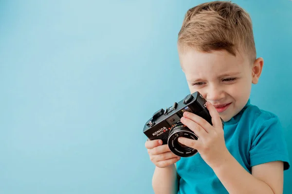 Niño pequeño con una vieja cámara sobre un fondo azul — Foto de Stock