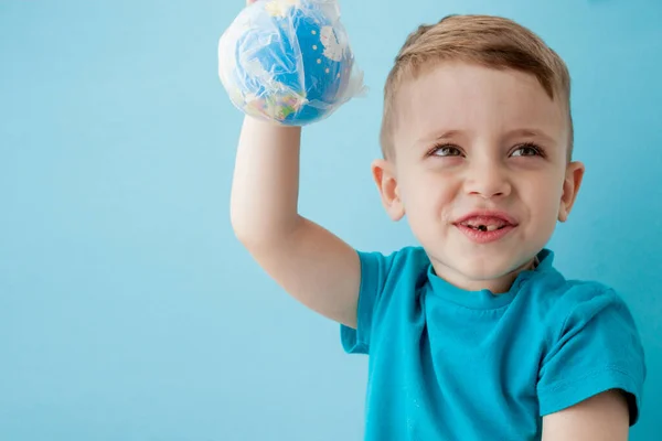 小男孩带着一个蓝色背景的包裹里的地球仪 — 图库照片