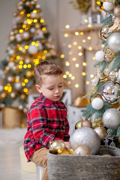 Menino não quer decorar a árvore de Natal. Feliz Natal e Feliz Ano Novo — Fotografia de Stock