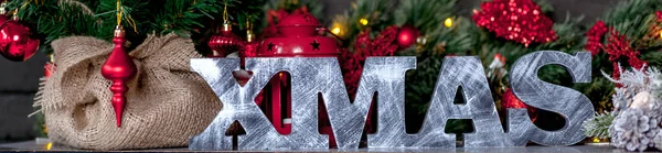 Christmas concept inscription Xmas made of wood on black backdrop.