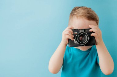 Kiev, Ukrayna - 10 Haziran 2019: Mavi arka planda eski bir kamerası olan küçük çocuk