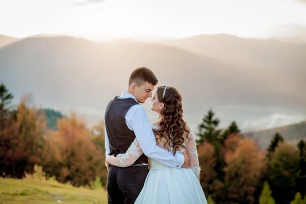 Nevěsta a ženich sledují západ slunce stojící na kopci — Stock fotografie