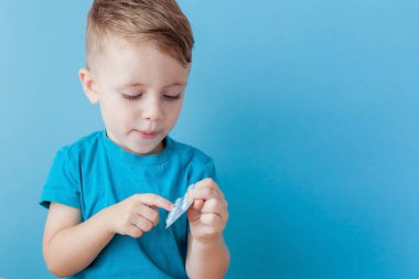 Küçük bir çocuk avucunun içinde mavi sırt üzerinde hap bir avuç tutar
