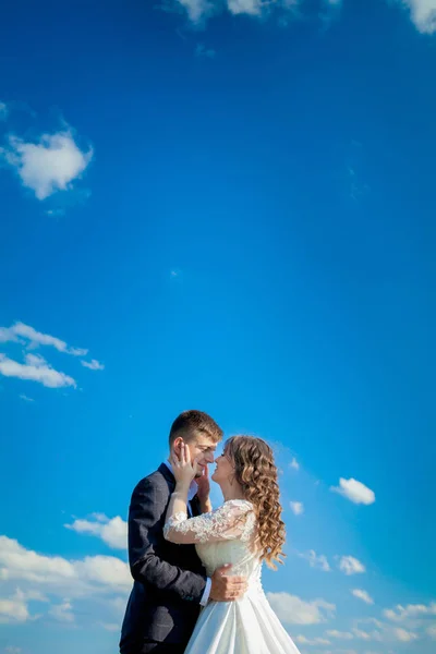 Novomanželé na pozadí modré oblohy.Svatební fotografie. — Stock fotografie