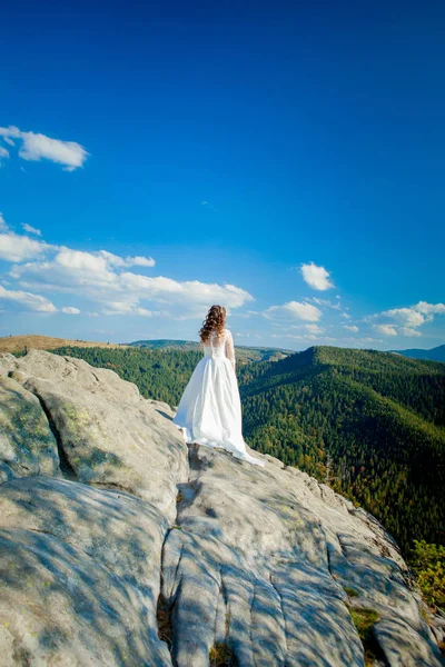 Indietro di ragazza in abito da sposa seduto su rocce in montagna e cercando di fiordo, escursioni in collina — Foto Stock