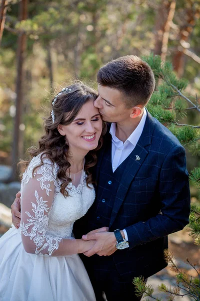 Schöne Frischvermählte, die sich vor der Kulisse von Felsen und Bergen umarmen. Stilvolle Braut und schöne Braut stehen auf der Klippe. Hochzeitsporträt. Familienfoto — Stockfoto