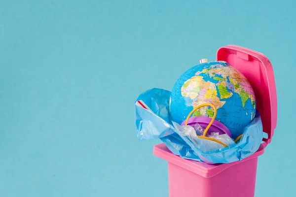 O globo terrestre está no lixo. O globo jaz num monte de plast — Fotografia de Stock