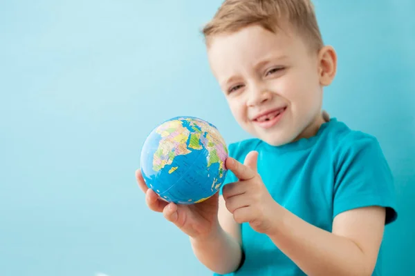 Little boy holding a globe on blue background — Stock Photo, Image
