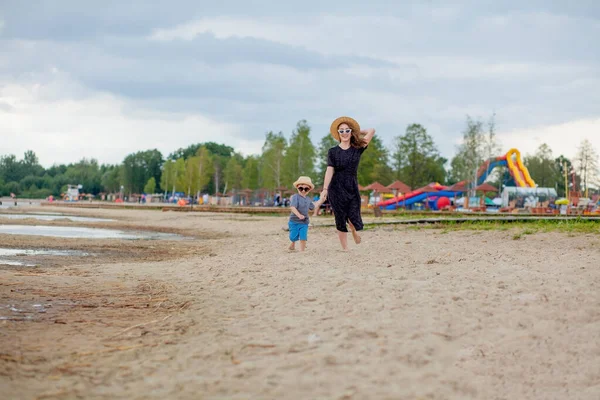 一个年轻漂亮的姑娘和她的儿子在沙滩上奔跑 — 图库照片