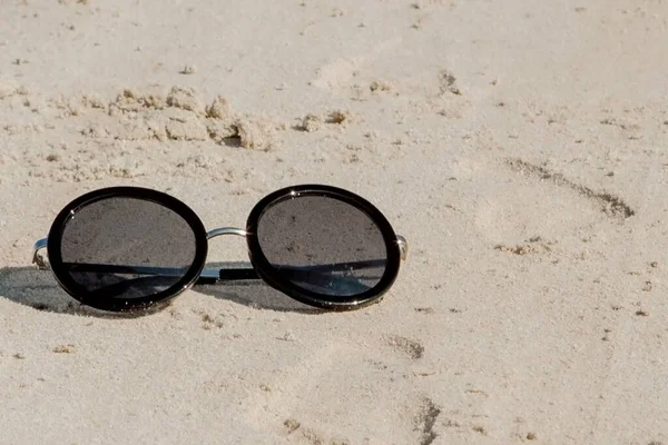Horní pohled na sluneční brýle na pláži v blízkosti modrého moře s pískem — Stock fotografie
