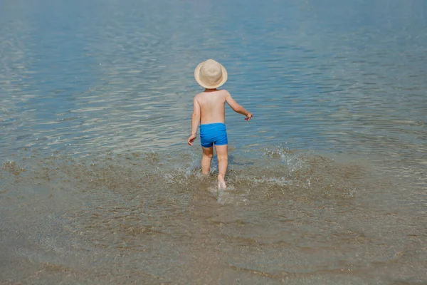 Cute little boy running through the water at the beach — Stock Photo, Image