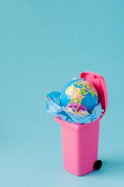 Dünya küresi çöpte yatıyor. Küre bir yığın plast içinde yatıyor.