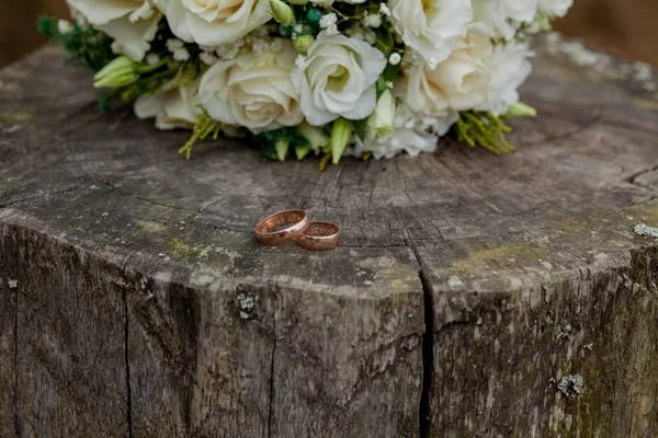 Wedding rings and bride's bouquet on stump, the bridal bouquet — Stock Photo, Image