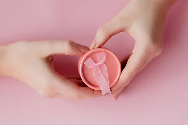Kotak hadiah merah muda di tangan wanita dengan latar belakang merah muda. Festi — Stok Foto