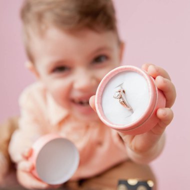 pembe arka plan üzerinde kutusunda halka veren çocuk
