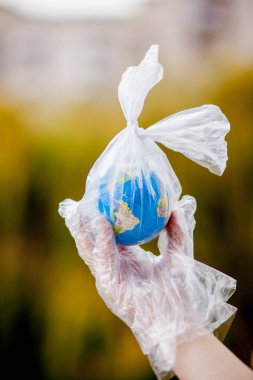 İnsan eli dünyayı plastik bir torba içinde tutuyor. Plastik molozlarla kirlilik kavramı. Sera etkisine bağlı küresel ısınma.