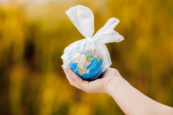 A mão humana segura o planeta Terra num saco de plástico. O conceito de poluição por detritos plásticos. Aquecimento global devido ao efeito estufa. — Fotografia de Stock