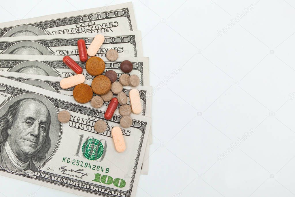 colored medicinal pills and american dollars on white a backgrou