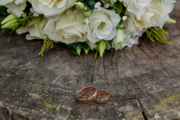 Обручальные кольца и букет невесты на пне, свадебный букет — стоковое фото