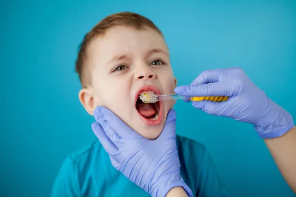 Piccolo ragazzo carino lavarsi i denti su sfondo blu — Foto Stock