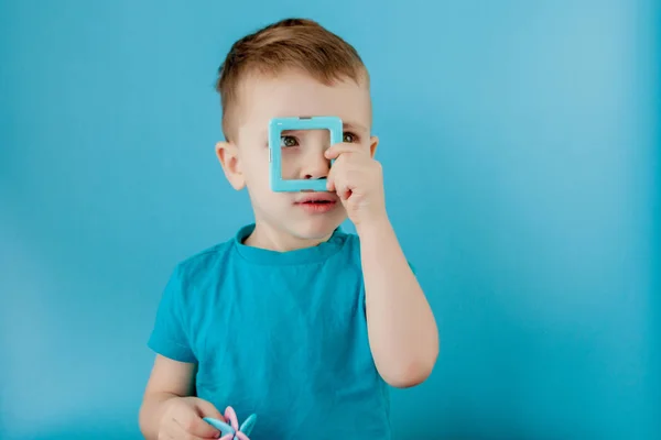 Rapaz olha através da forma no construtor de cores com a conexão dos ímãs — Fotografia de Stock