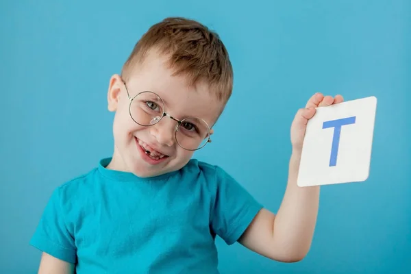 Menino bonito com carta no fundo azul. Criança a aprender cartas. Alfabeto — Fotografia de Stock