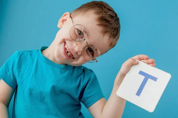 Leuke kleine jongen met een brief op een blauwe achtergrond. Een kind dat een brief leert. Alfabet — Stockfoto