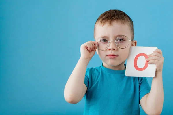 可爱的小男孩，蓝色背景的字母。孩子在学字母。字母拼音 — 图库照片