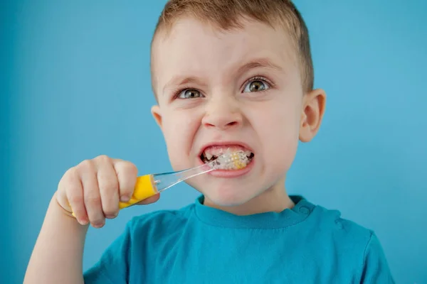 Pequeño chico lindo cepillándose los dientes sobre fondo azul — Foto de Stock