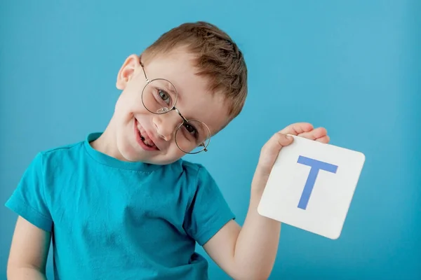 Lindo niño con letra sobre fondo azul. Niño aprendiendo cartas. Alfabeto —  Fotos de Stock