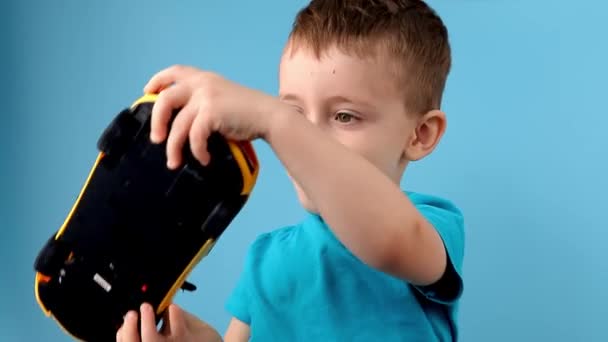 Kleine Jongen Spelen Met Een Grote Gele Auto Blauwe Achtergrond — Stockvideo