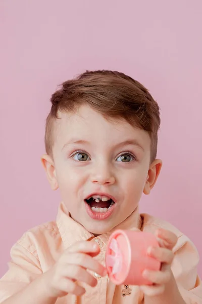 Glad liten pojke med en gåva. Foto isolerad på rosa bakgrund — Stockfoto