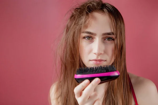 Menina bonita nova que tem problemas enquanto o cabelo no fundo rosa — Fotografia de Stock