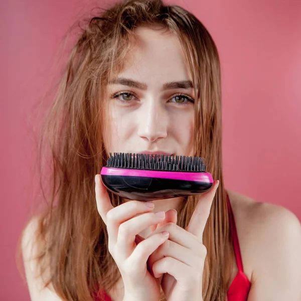 Menina bonita nova que tem problemas enquanto o cabelo no fundo rosa — Fotografia de Stock