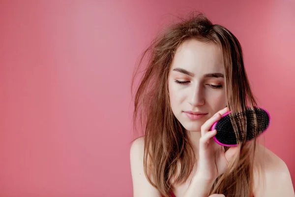 Junge schöne Mädchen mit Problemen, während die Haare auf rosa Hintergrund — Stockfoto
