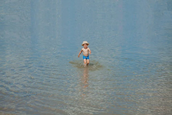 Gelukkig baby loopt van surf op het strand — Stockfoto