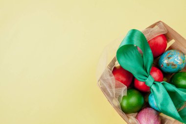 Mutlu Paskalya yumurtaları sarı arka plan. Kutlama kartı, promosyon ve poster için sepetteki altın parlayan yumurtalar. Boşluğu kopyala