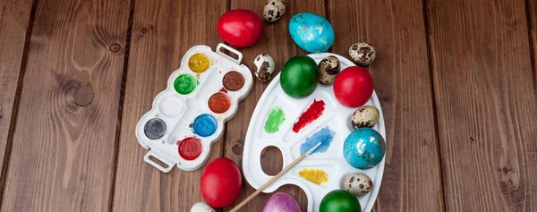 Ovos coloridos e tinta em uma mesa de madeira, fundo de Páscoa — Fotografia de Stock