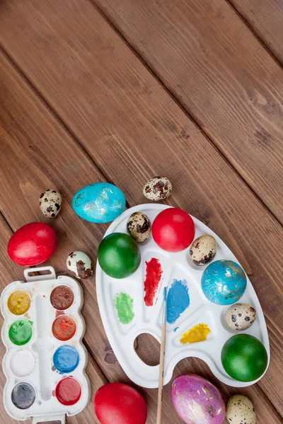 Ovos coloridos e tinta em uma mesa de madeira, fundo de Páscoa — Fotografia de Stock