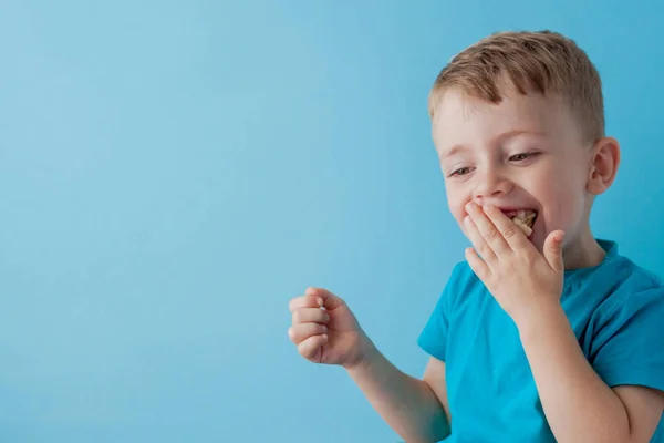 Little Boy Segurando e comendo uma banana no fundo azul, comida — Fotografia de Stock