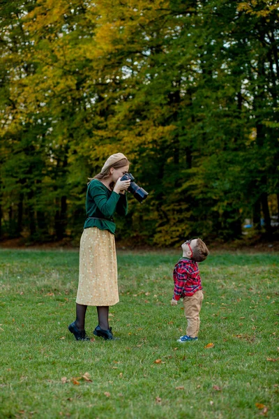Mulher fotógrafa fotografa a criança para passar fora em t — Fotografia de Stock
