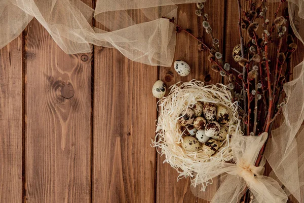 Huevos de codorniz de Pascua en el nido y la rama de sauce sobre un fondo de madera, espacio de copia — Foto de Stock