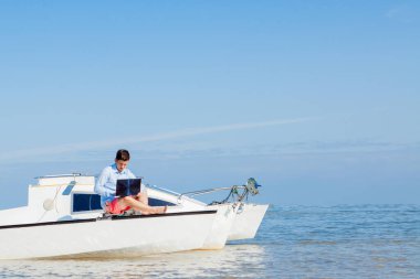 Yelkenlide dizüstü bilgisayarı olan genç ve yakışıklı bir adam. Serbest çalışma konsepti