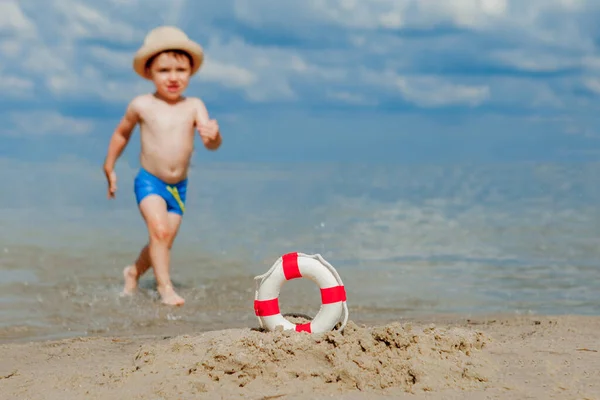 Zbliżenie z Lifebuoy na plaży na tle dziecka. Bezpieczeństwo na wodzie. — Zdjęcie stockowe