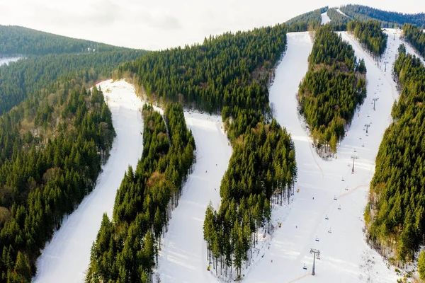 Aerial view of landscape of ski and snowboard slopes through pine trees going down to winter resort in Carpathians — Stock Photo, Image