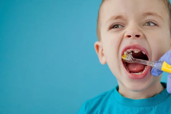 Piccolo ragazzo carino lavarsi i denti su sfondo blu — Foto Stock